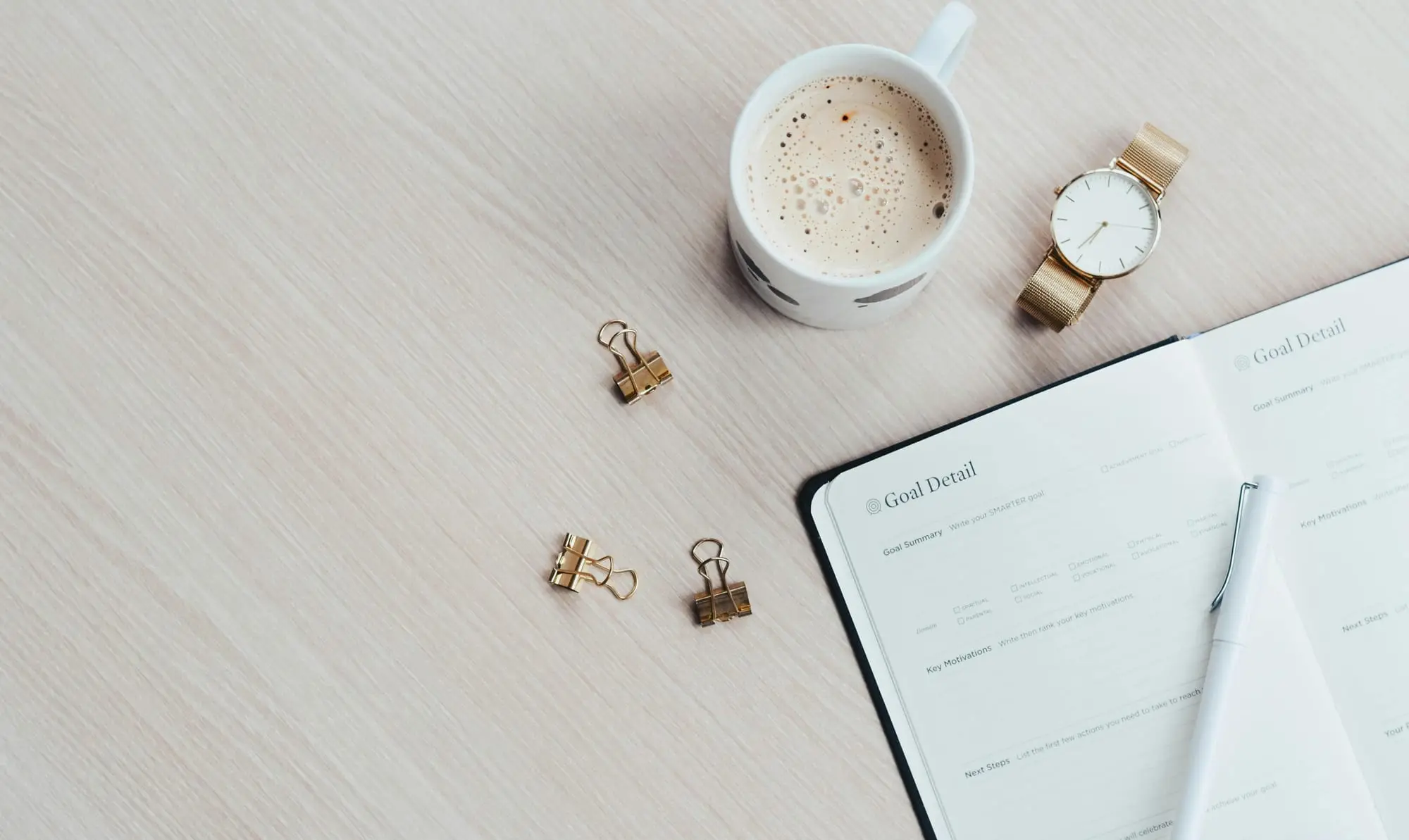 Notebook, coffee cup and watch on a desk