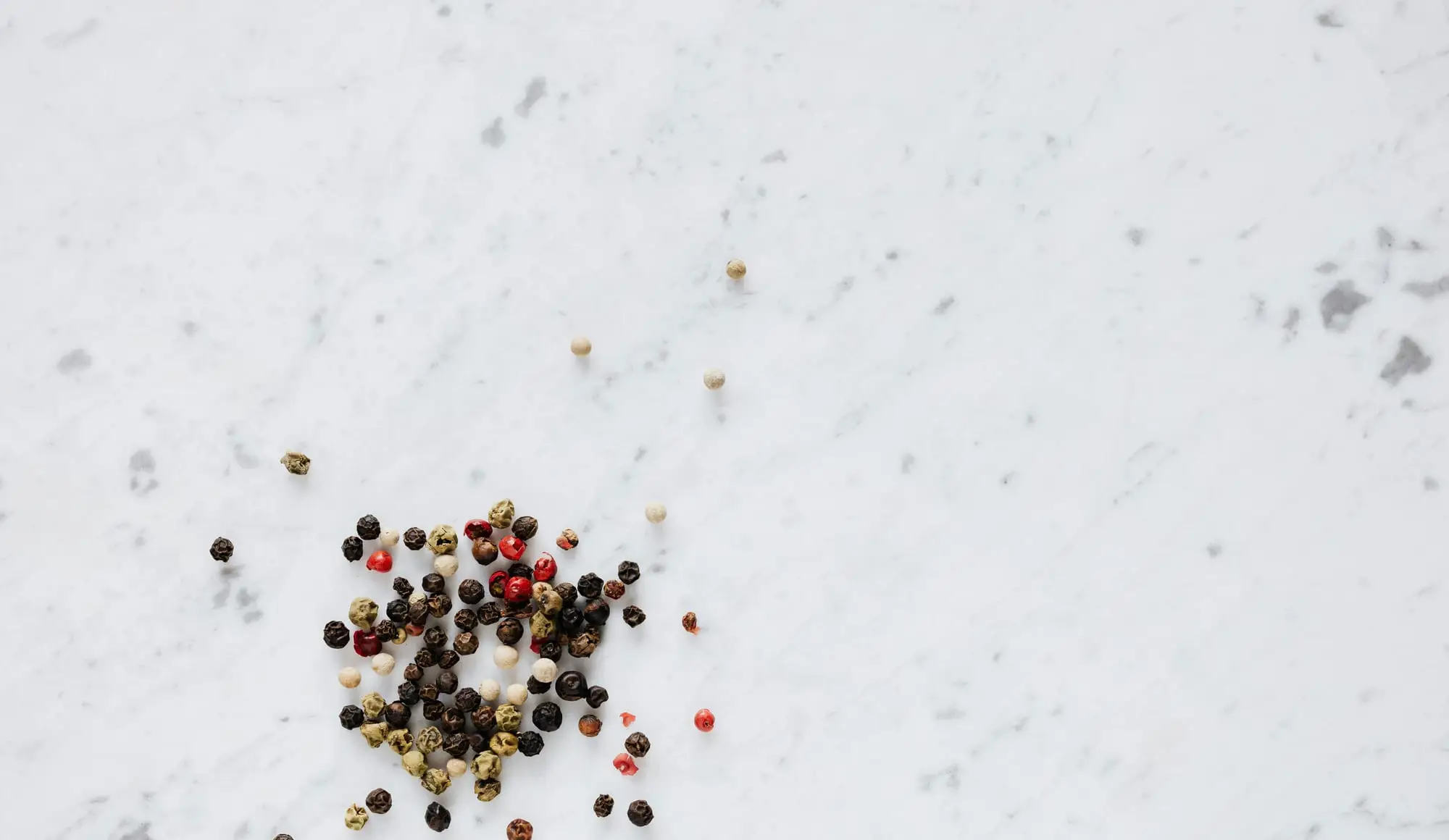 Mixed peppercorns on a white surface